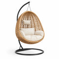 Poltrona sospesa a uovo in rattan sintetico marrone naturale con supporto nero e cuscini crema, 105 × 105 × 195 cm